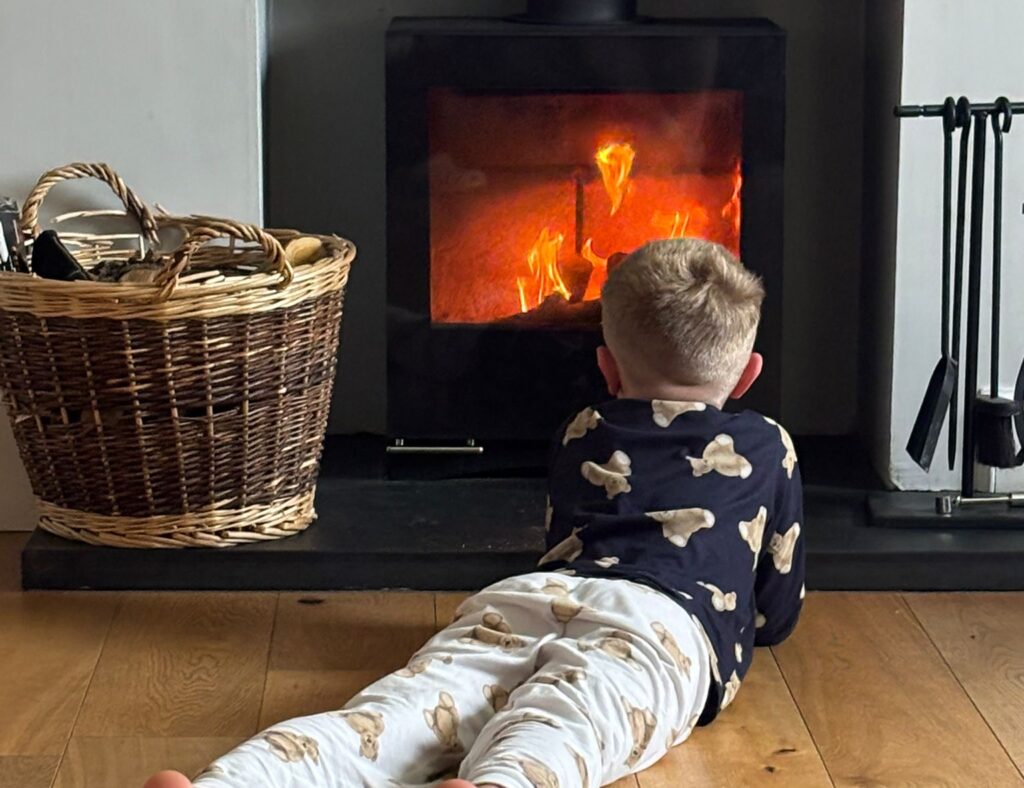 Child relaxing by a cosy wood burning stove during a family winter holiday in Scotland
